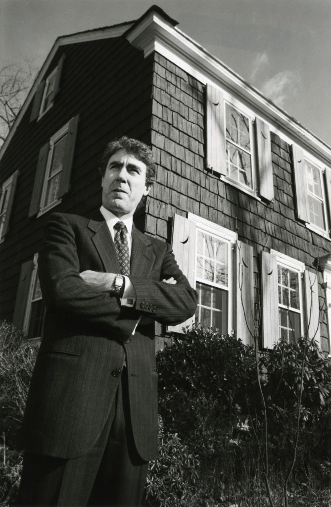 Douglas Cooper, a distinguished New Rochelle lawyer who served for 10 years as the President of the Thomas Paine Historical Association stands at the Paine Cottage - Westchester County Historical Society
